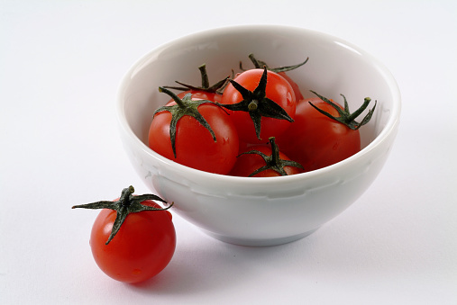 Bowl with fresh tomatoes on wooden surface