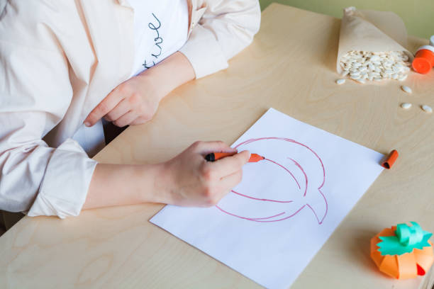 istock Making pumpkin from seeds on white paper, Halloween DIY concept 1359387343