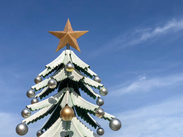 istock decorated noel tree shaped statue over beautiful blue sky in a sunny day for new year. 1359393147