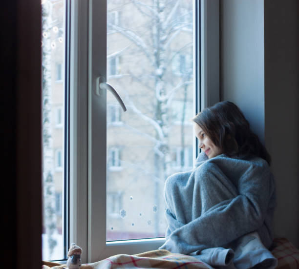 istock The girl is sitting by the window 1359402992