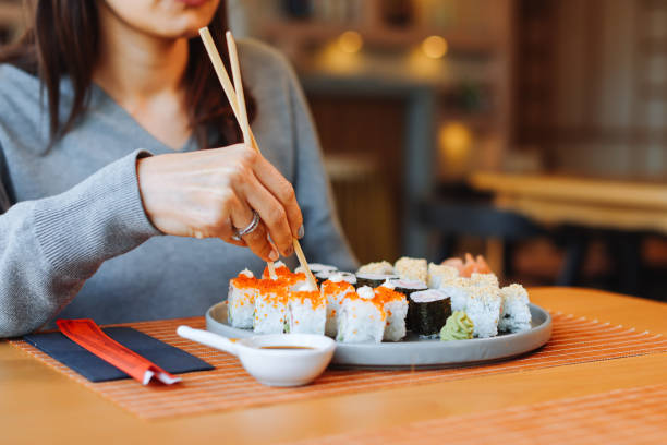 istock Young woman eating sushi rolls 1359404202