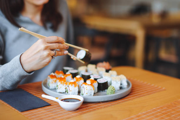 istock Young woman eating sushi rolls 1359404357