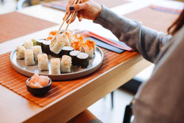 istock Young woman eating sushi rolls 1359404496