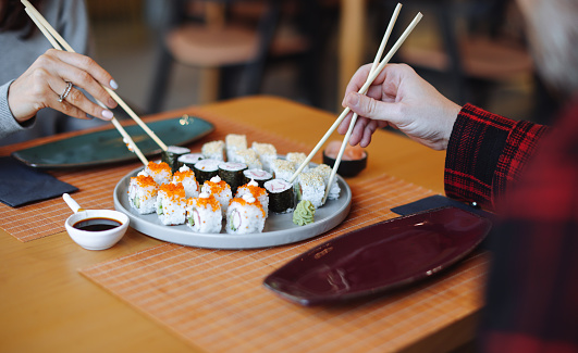 Close-up, couple hands eating sushi food with chopsticks