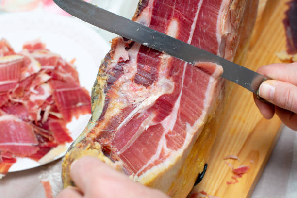 cortar pata de jamón serrano con un cuchillo, al fondo un plato de jamón serrano partido - spanish cuisine fotografías e imágenes de stock