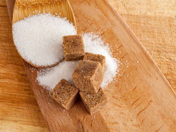 istock Brown cane sugar in cubes and white crystalline sugar, top view, types 1359410876