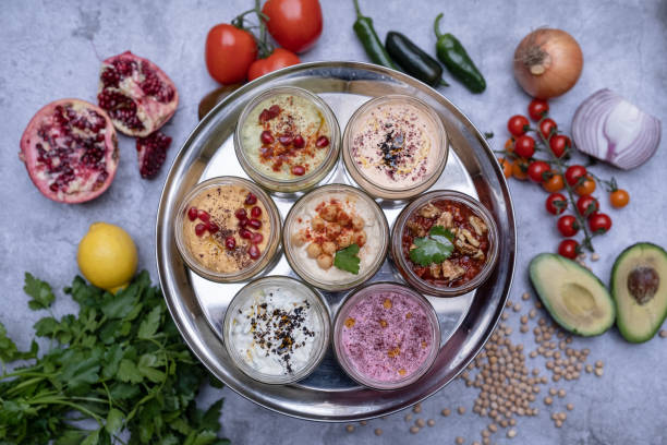 Tabletop View Tray of Mezes A tabletop view of a metal tray filled with small plates of mezes, half a pomegranate, onion, tomatoes, avocado, pepper and a bunch of parsley seen blurry on the table. meze stock pictures, royalty-free photos & images