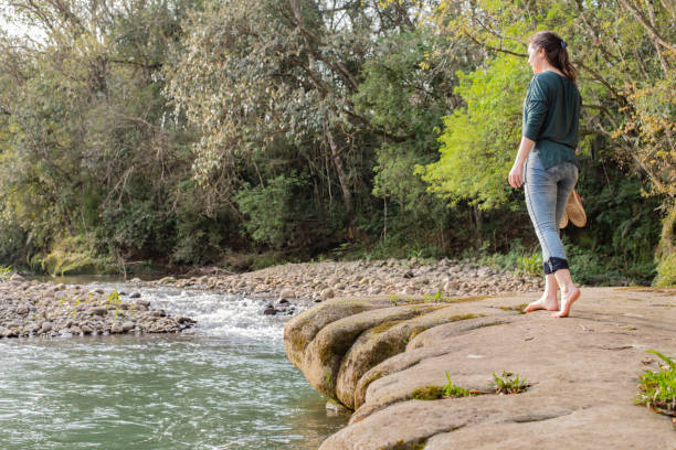 istock Woman walking on rocks barefooted with her shoes in hands 1359418421