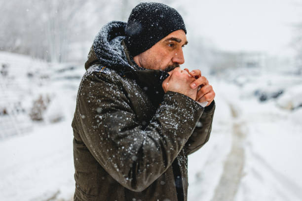 portrait shot of the caucasian good looking mature  man in casual style is freezing on the cold winter day while standing in the center city. - congelação imagens e fotografias de stock