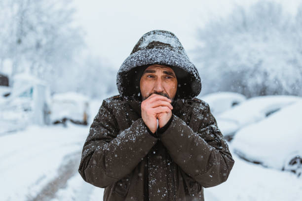 Portrait shot of the caucasian good looking mature  man in casual style is freezing on the cold winter day while standing in the center city. stock photo