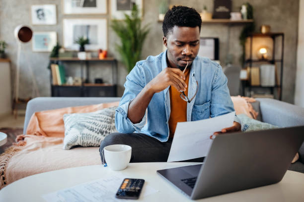 Shot of a young man going over his finances at home