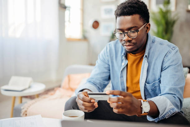 istock Young handsome man holding credit card in his hands 1359420216