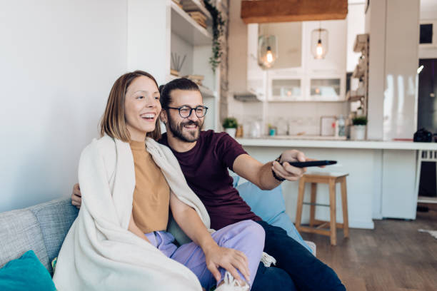 istock Young couple enjoying a cozy weekend, watching TV 1359420241