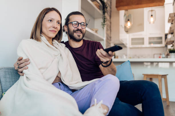 istock Young couple watching TV at home and having fun 1359420242