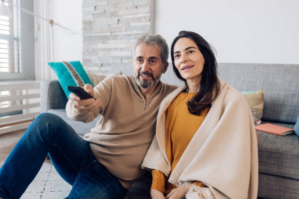 istock Happy couple watching TV at home 1359420398