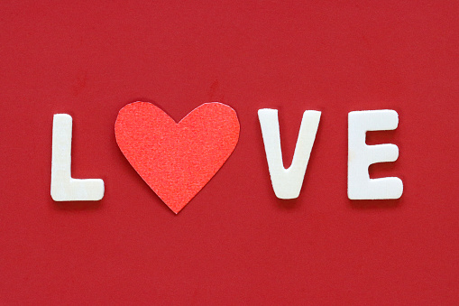 Stock photo showing elevated view of red background with white lettering, Valentine's Day greeting card sign.