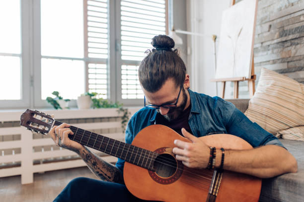 istock Young man playing a guitar and enjoying at home 1359425211