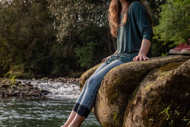 istock Woman sitting on the rock at waterfall 1359434658