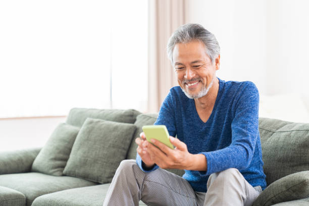 uomo anziano che usa lo smartphone, - 60 anni foto e immagini stock