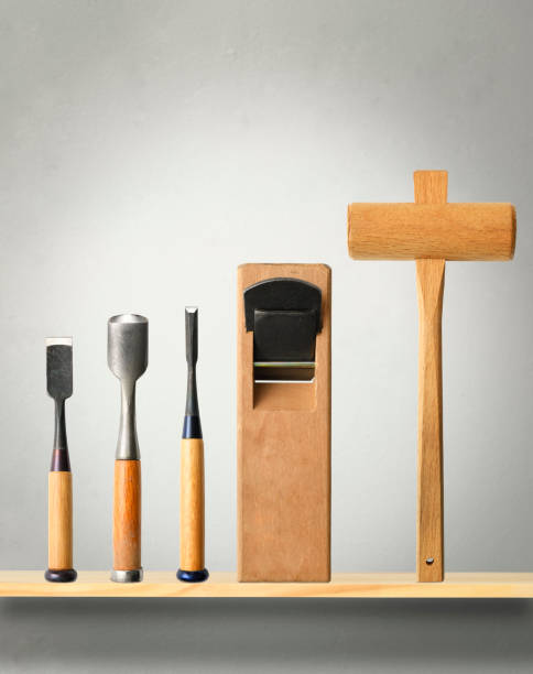 Close-up of carpentry tools lined up on the shelf against concrete wall.