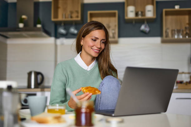 istock Young woman doing a video call on her laptop during breakfast 1359444125