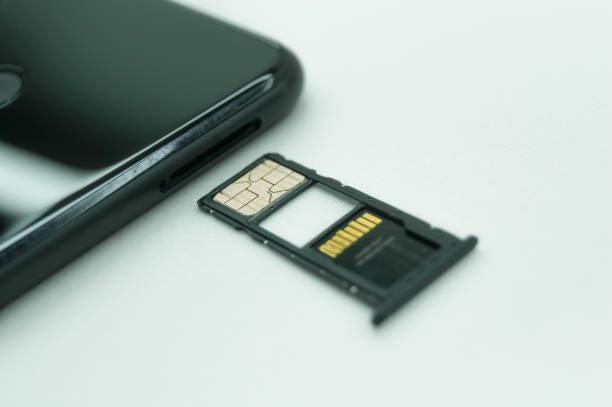 istock Installing a SIM card in a mobile phone. Open tray for SIM cards and micro memory cards. Selective focus, white background 1359445978