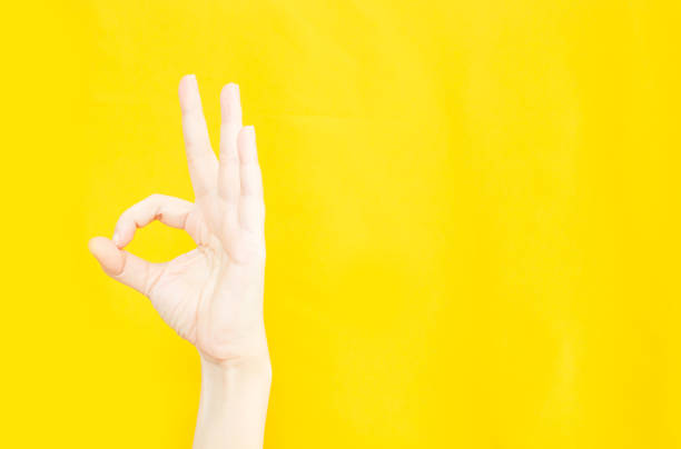 istock woman's hand with OK or agreement gesture  in copy space area for advertisement promotion or text on a yellow background 1359447218