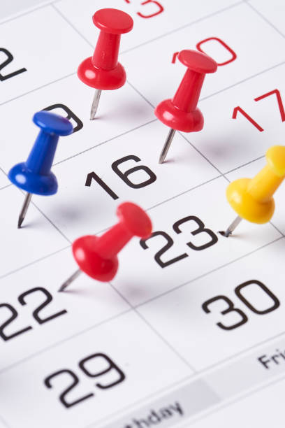 pinos de empurrão coloridos na página do calendário mensal - calendar calendar date reminder thumbtack - fotografias e filmes do acervo