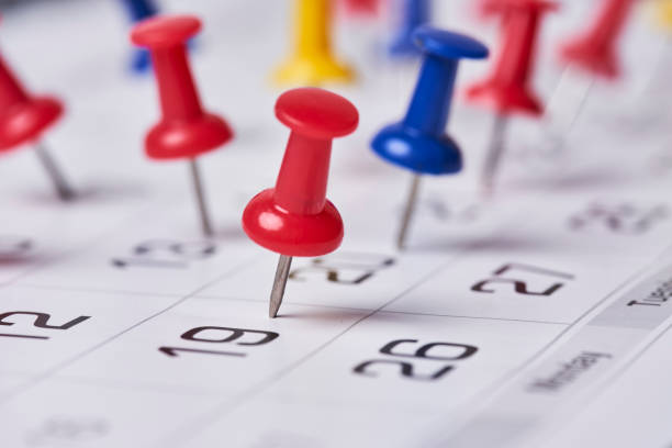 Colored push pins on monthly calendar page stock photo