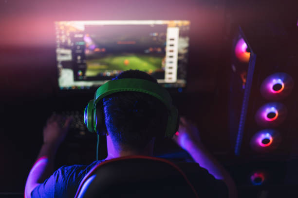 istock The guy plays at the computer in green headphones under neon light 1359454744