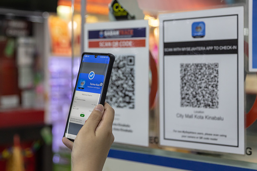 Kota Kinabalu, Sabah, Malaysia-March 06, 2021 : citizen using Smartphone scanning Mysejahtera apps before enter shop to assist the Government in managing and mitigating the COVID-19 outbreak.