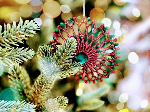 istock Simplistic magical holiday background of bokeh effect light surrounding single red geometric ornament on boughs of evergreen - stock photo 1359460268