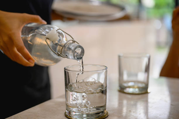 pouring water from a glass bottle into a glass - water water bottle glass pouring imagens e fotografias de stock