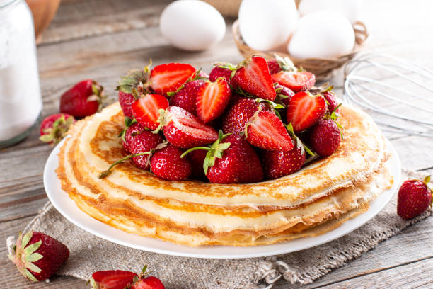 istock Many pancakes with strawberries. Maslenitsa. A stack of thin freshly baked pancakes with strawberry berries 1359467122