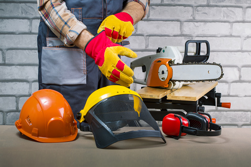 Worker puts protective gloves in workshop. Safety protective equipment and lumberjack.