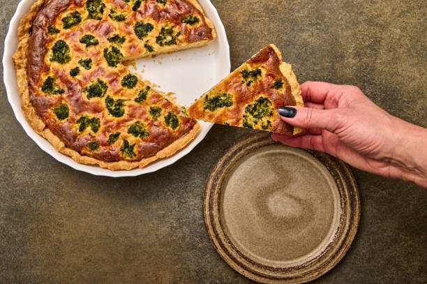 istock Woman's hand puts piece of quiche pie on ceramic rustic plate 1359471555