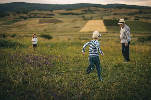 Two little kids spending time in nature with grandfather