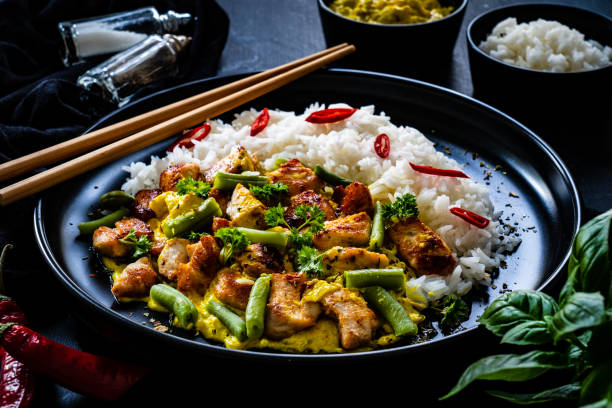 istock Roast chicken meat, white rice and vegetables on wooden table 1359472137