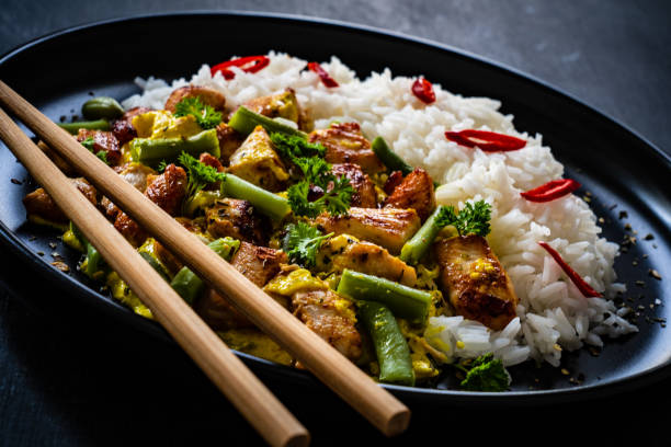 istock Roast chicken meat, white rice and vegetables on wooden table 1359472159