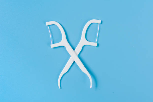 istock Plastic white dental toothpick with dental floss on blue background. 1359473351