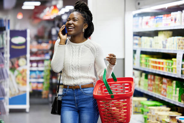 photo d’une jeune femme passant un appel téléphonique alors qu’elle se promenait dans l’épicerie - supermarket discussion people talking photos et images de collection