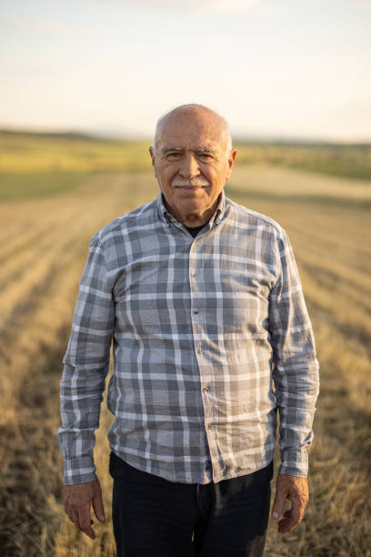 istock Senior man standing in field on sunny day and looking at camera 1359479030