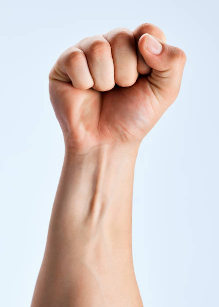 Shot of an unrecognizable man holding his fist up against a white background It's our time to rise anonymous activist network stock pictures, royalty-free photos & images