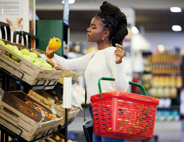 Shot of a young woman browsing through the produce section of a grocery store Picking the correct produce makes the difference holding shopping basket stock pictures, royalty-free photos & images