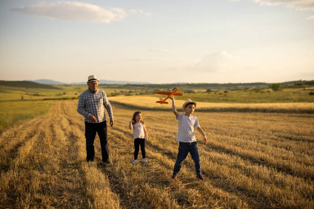 istock Grandfather spending time with two kids in nature while they playing with airplane toy 1359481664