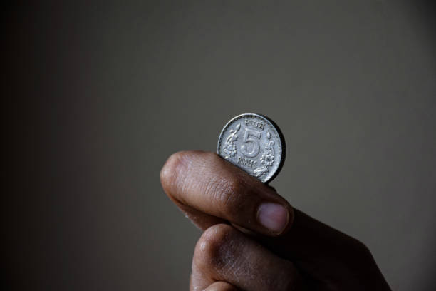 Stock photo of a man holding five rupees coin Indian currency on blur background at Bangalore, Karnataka, India. focus on object stock photo