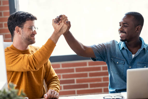 istock Two graphic designer working with laptop while celebrating something shaking hands in modern startup office. 1359482820