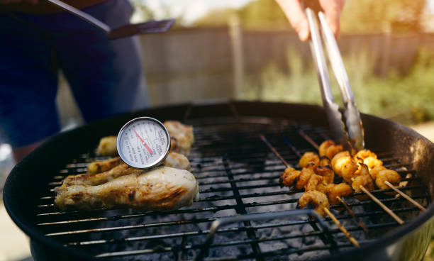 ein lebensmittelthermometer, das überprüft, ob das huhn auf einem grill korrekt gekocht wird. - barbecue chicken stock-fotos und bilder
