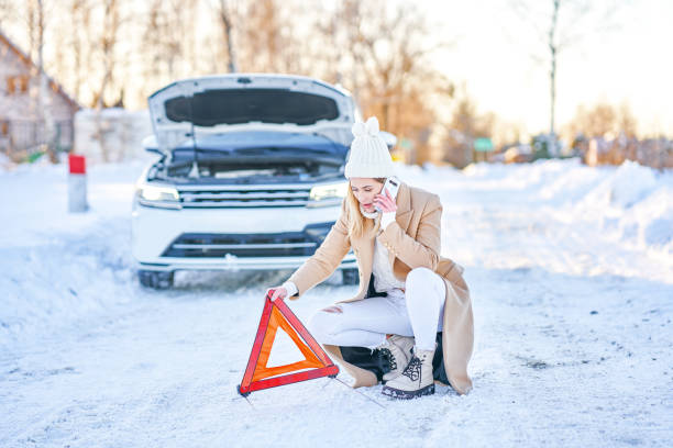 junge frau mit autoproblemen im winter - emergency sign winter driving emergency services stock-fotos und bilder