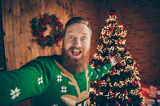 Photo of amazed hospitable blogger guy shoot selfie invite x-mas party wear deer sweater decorated office indoors